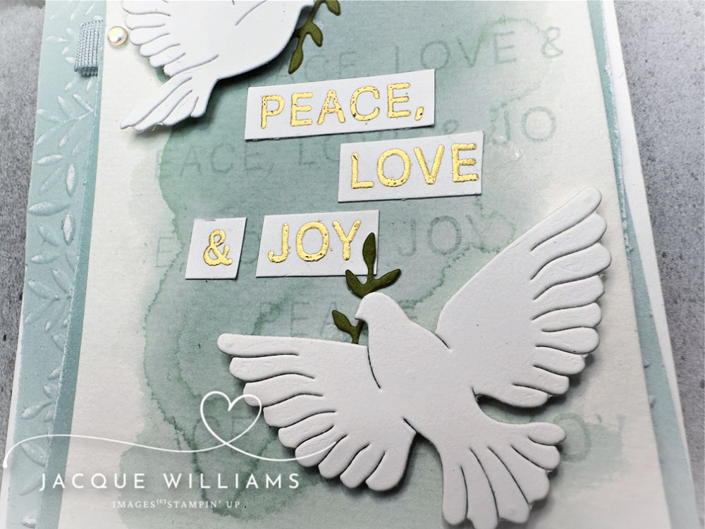 Handmade Christmas card featuring the Stampin’ Up! Peaceful Garden suite with two white die-cut doves holding olive branches. The card has a soft watercolor background in Pool Party with embossed leaves and the sentiment “Peace, Love & Joy.” Perfect DIY cardmaking idea for Christmas, weddings, or sympathy cards.