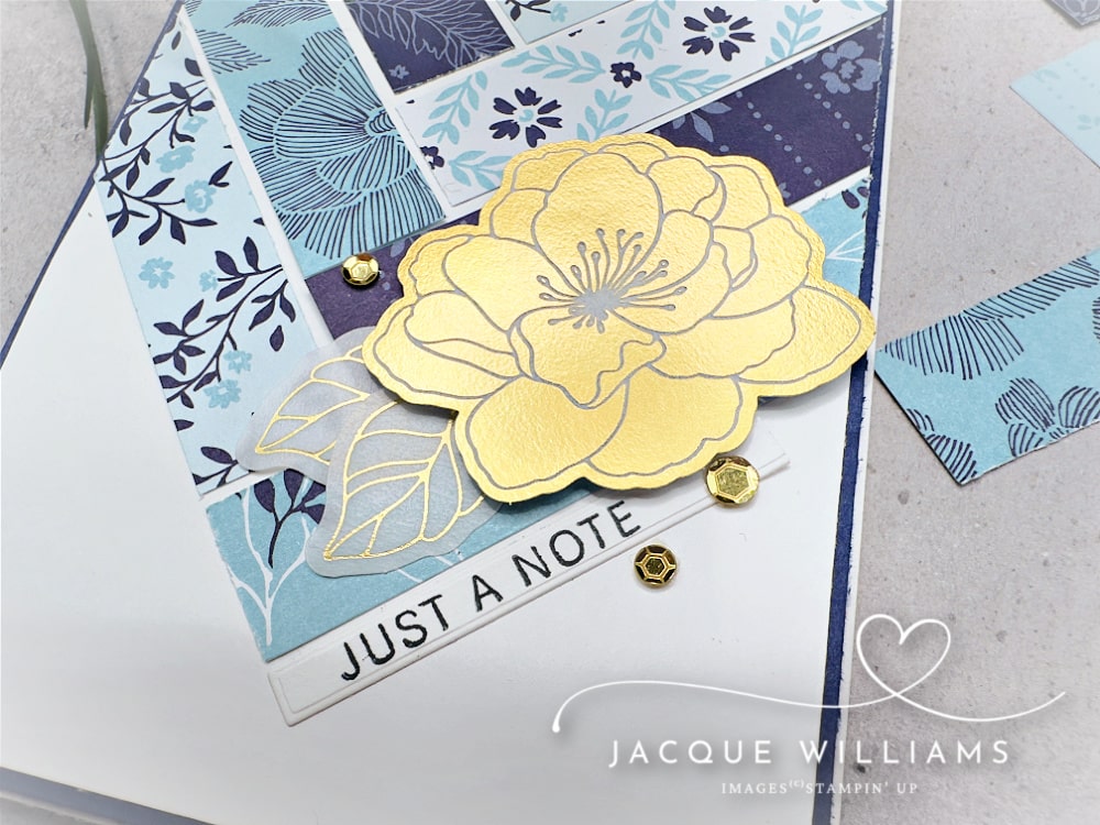 Handmade Stampin’ Up! card featuring the True Blue Designer Series Paper layered in a modern geometric layout, accented with a yellow floral die cut from the Beautifully Ornate Ephemera Pack. Clean and simple cardmaking design with navy, soft blue, and white tones, gold embellishments, and a “Just a Note” sentiment—ideal for everyday handmade cards and paper crafting inspiration.